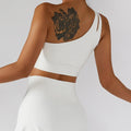Woman in white one-shoulder sports bra and skirt, part of a piece tennis suit for women sport
