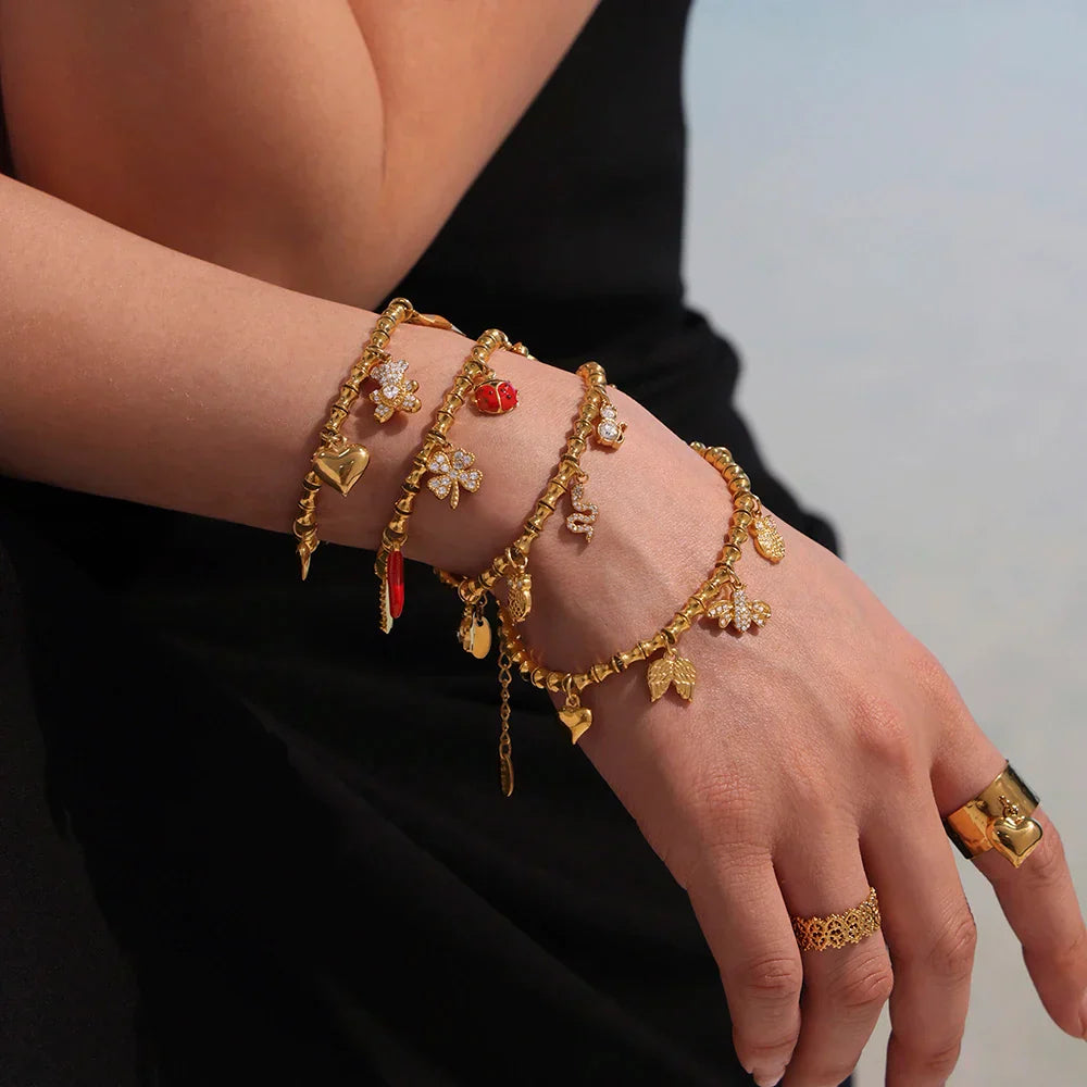 Elegant gold charm bracelets with cubic zircon rings on woman’s hand