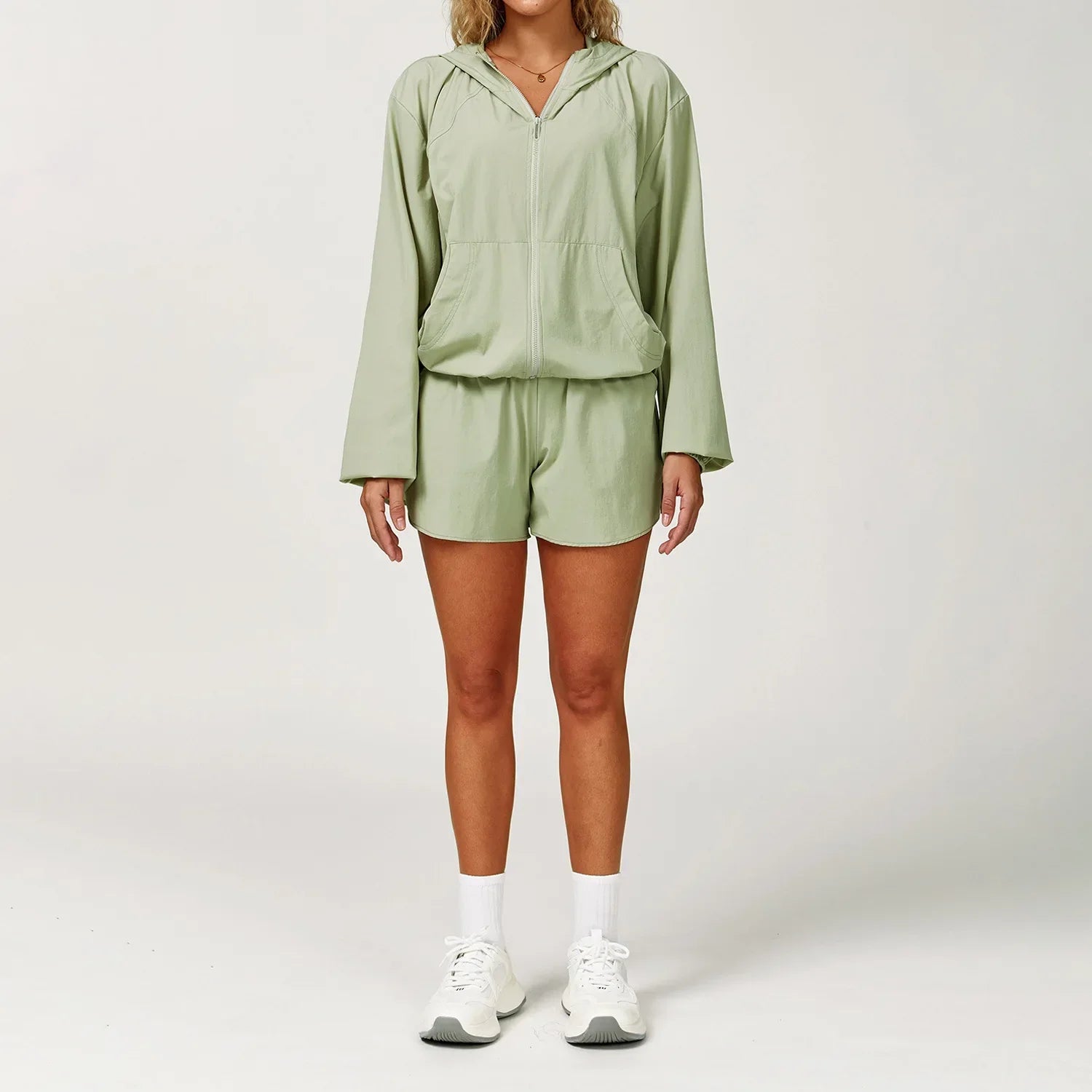 Woman in light green windbreaker dress with hood for gym yoga