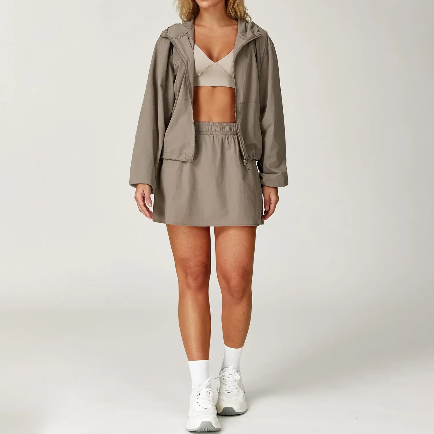 Women’s taupe yoga set with hooded windbreaker jacket, sports bra, and mini skirt