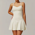 Woman modeling off-white strappy mini dress with fitted bodice and flared skirt