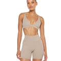 Woman in stretchy soft training set: beige compression sports bra and biker shorts