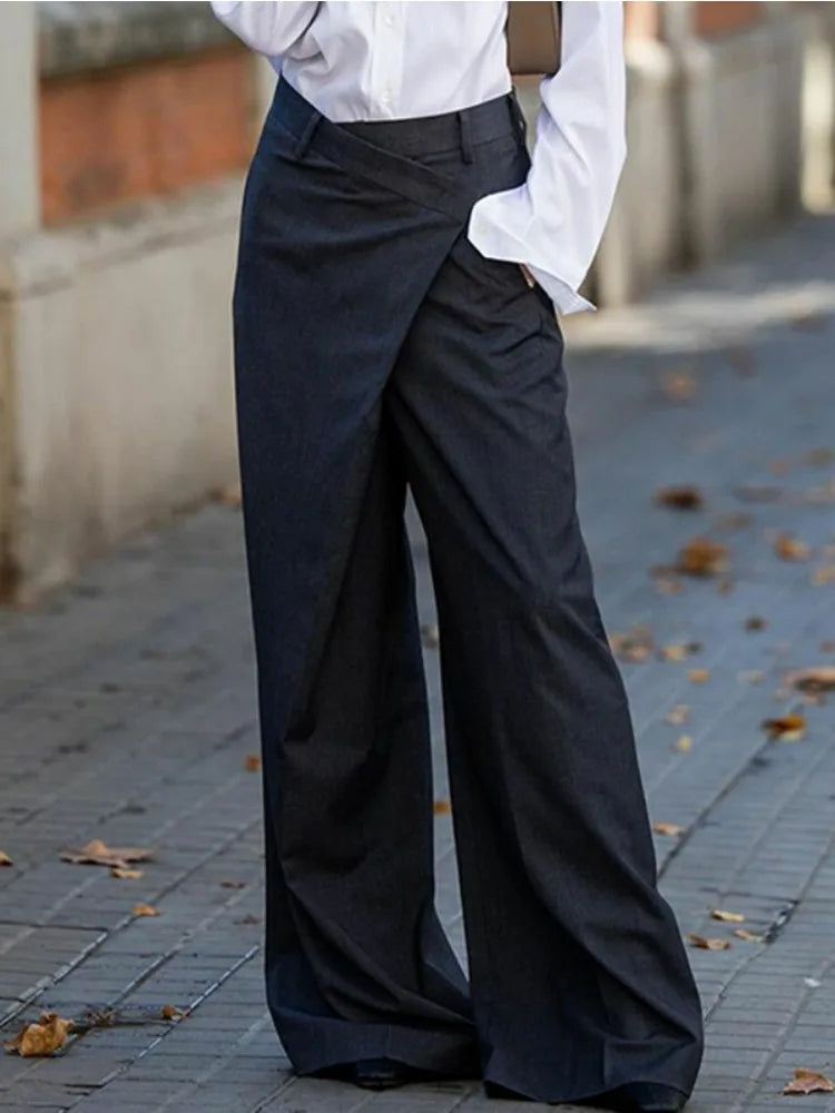 Woman in white collared shirt and casual suit pants holding brown handbag