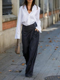 Woman in white collared shirt and casual suit pants holding brown handbag